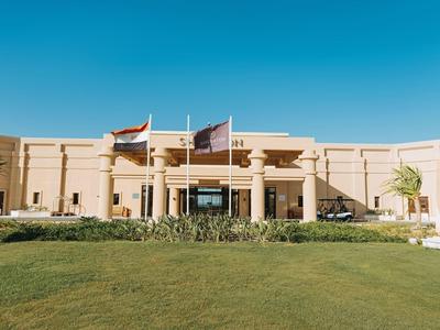 Ein florierendes Hotelgebäude mit Flaggen und grünem Rasen im Vordergrund unter klarem blauem Himmel.