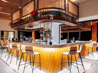 Moderner Barbereich mit hoher Bestuhlung und warmem Holzdesign in einem Hotel.