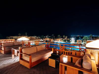 Nachtterrasse mit Holzmöbeln und Lichtern in einem Hotel mit Blick auf Stadtlichter.