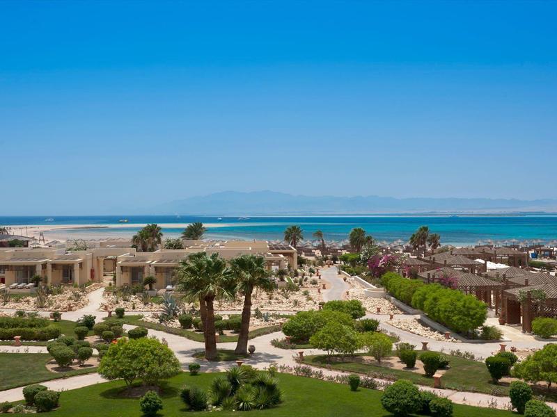 Blick auf Küstenstadt mit Sandstrand, Palmen, Gebäuden und klarem blauem Himmel.
