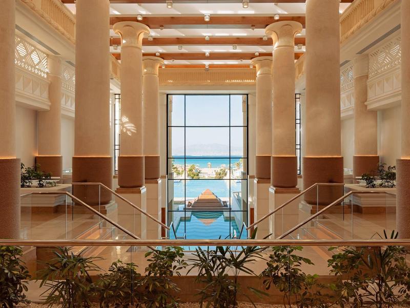 Luxuriöse Hotellobby mit Säulen und Blick auf Pool und Meer durch große Fenster