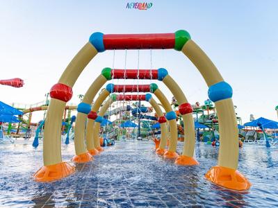 Bunter Wasserspielplatz mit Rutschen und Spritzbogen unter klarem Himmel am Schwimmbad.