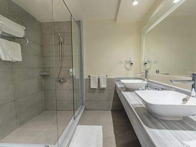 Modernes Badezimmer mit Glas-Duschabtrennung, zwei Waschtischen und großem Spiegel.