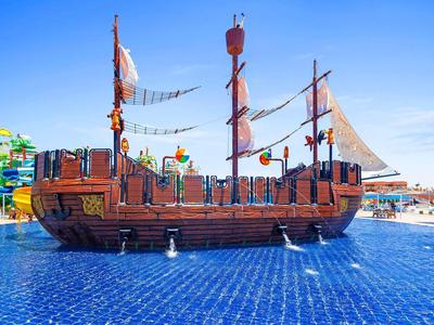 Großes hölzernes Piratenschiff im blauen Wasserbecken auf einem sonnigen Freizeitpark.