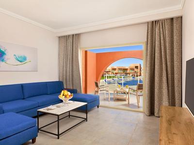 Helles Wohnzimmer mit blauer Eckcouch, Holzmöbel, Kunst an der Wand und Balkon mit Meerblick.