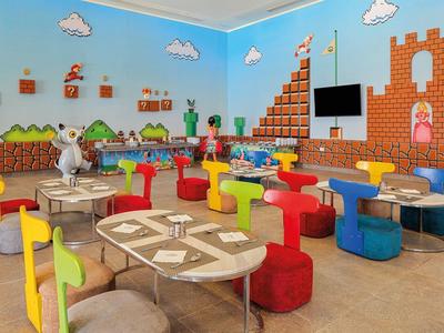 Colorful Mario-themed play area with tables, chairs, and wall decorations.