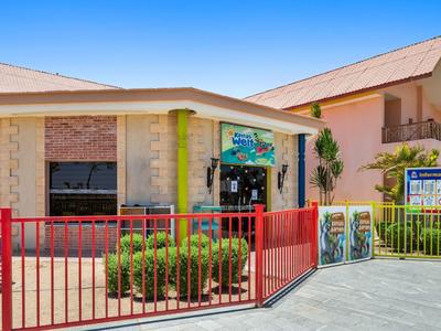 Exterior view of a building with a red fence and multiple signs under clear sky.