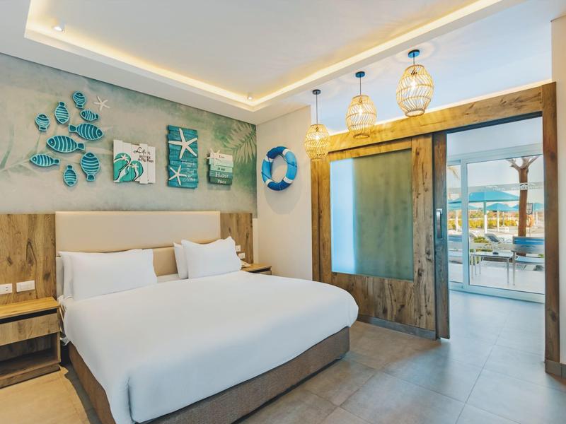 Modern hotel room with double bed, nautical decor, and view of a terrace.