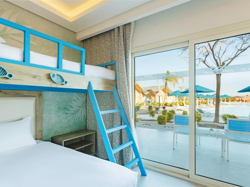 Hotel room with bunk bed, large window, and view of terrace and sea.