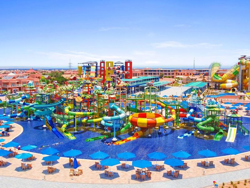 Colorful waterpark with slides and pools surrounded by sun umbrellas on a sunny day.