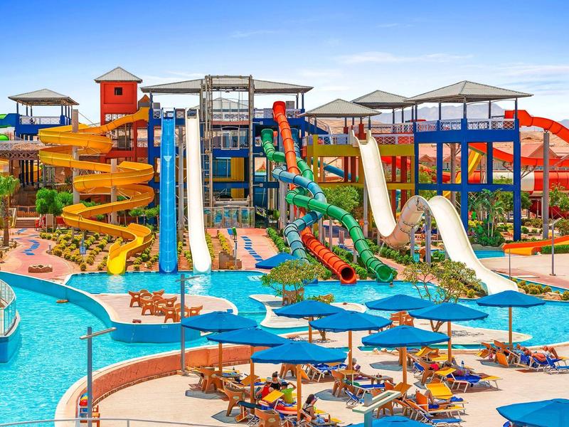 Colorful water park with slides, pools, and shaded lounge chairs on a sunny day.
