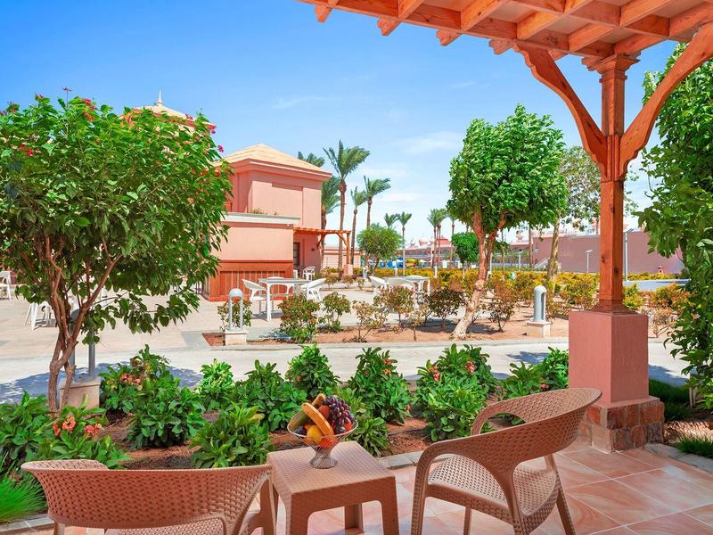 Outdoor seating area in a sunny, colorful garden at a vacation resort.