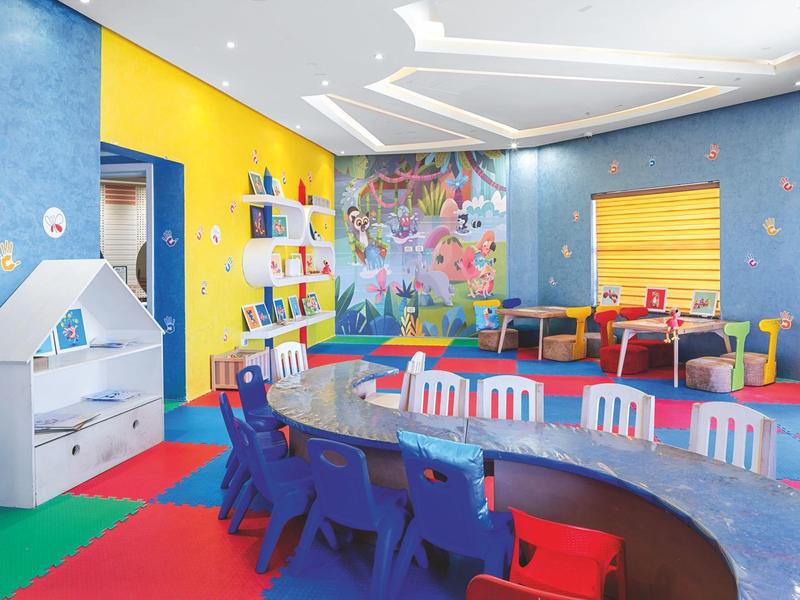 Colorful playroom with children's furniture, vibrant carpet, and wall decorations.
