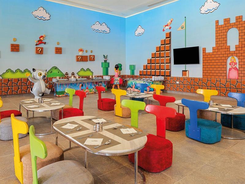Colorful Mario-themed play area with tables, chairs, and wall decorations.