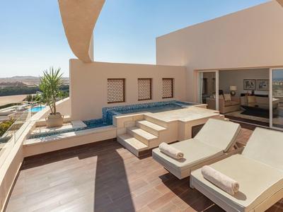Modern balcony with lounge chairs and a small pool overlooking a scenic landscape.