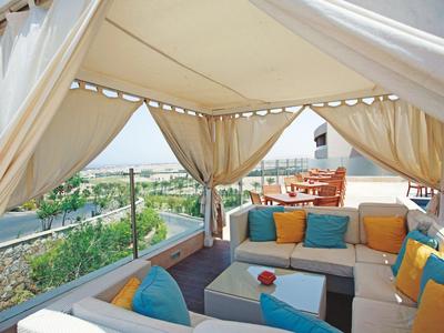 Accogliente terrazza sul tetto con divano e tende, vista sulla città e natura.