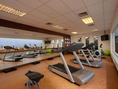 Palestra luminosa con tapis roulant, parete a specchio e grandi finestre.