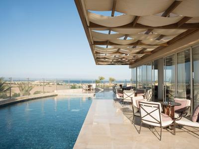 Zona piscina moderna con posti a sedere sotto una tenda e vista sul mare
