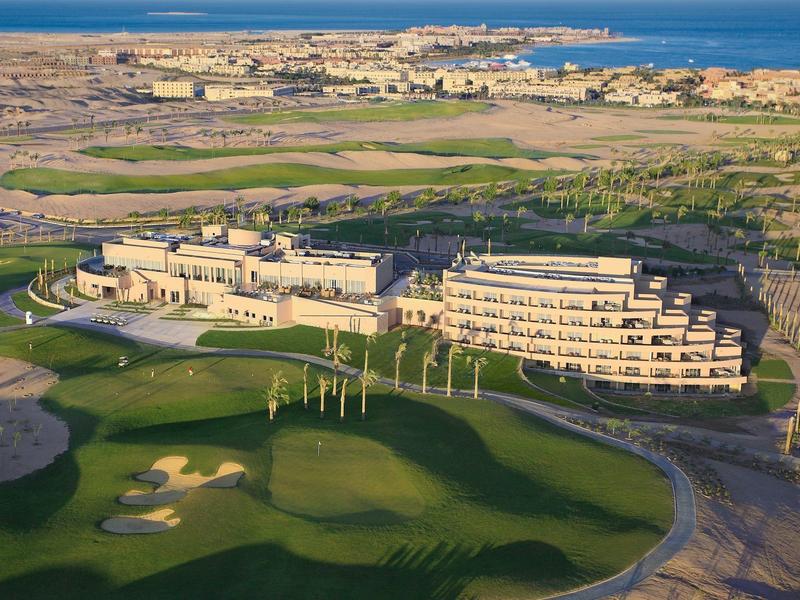 Resort hotel near a golf course with desert surroundings and sea in the distance.