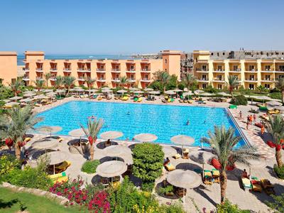 Large outdoor pool with umbrellas and lounge chairs at a hotel resort under blue sky