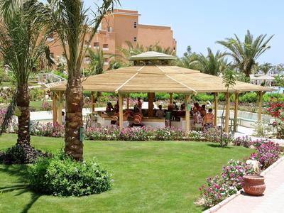 Green garden area with palm trees and covered seating under clear sky