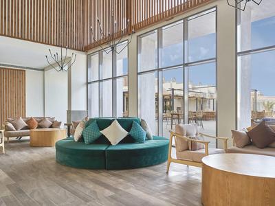 Helles Hotel-Lounge mit großen Fenstern, modernen Möbeln und Holzakzenten.