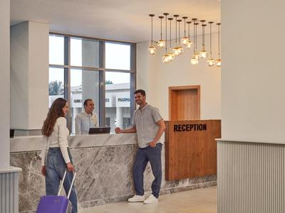 Hotelrezeption mit Empfangspersonal und Gästen mit Gepäck im modernen Eingangsbereich