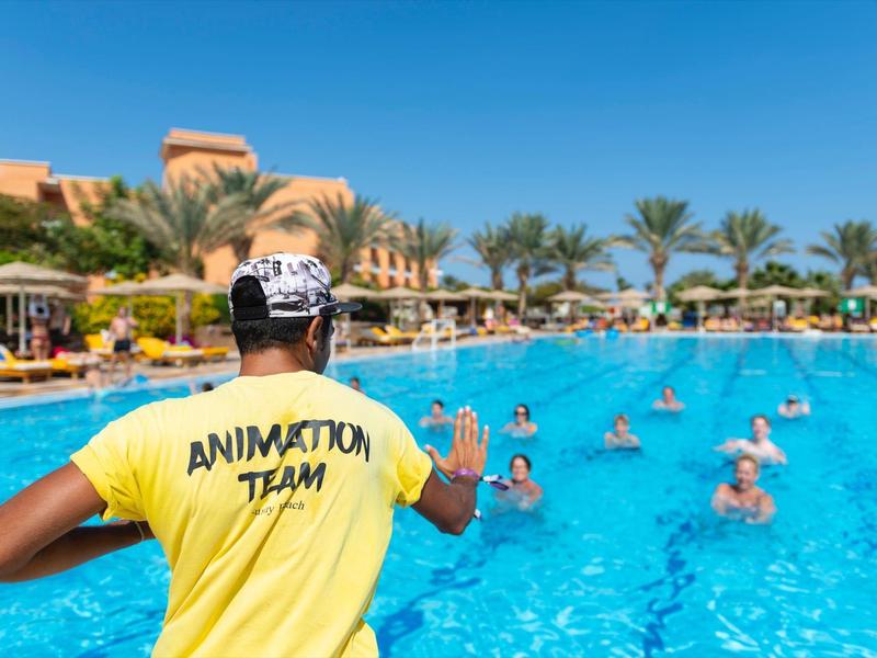 Animationsteam-Mitglied im gelben Shirt leitet Wassergymnastik im Hotelpool an