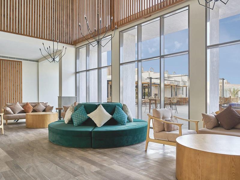 Helles Hotel-Lounge mit großen Fenstern, modernen Möbeln und Holzakzenten.