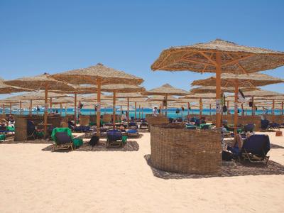 Sandy beach with straw umbrellas and lounge chairs under a clear blue sky.