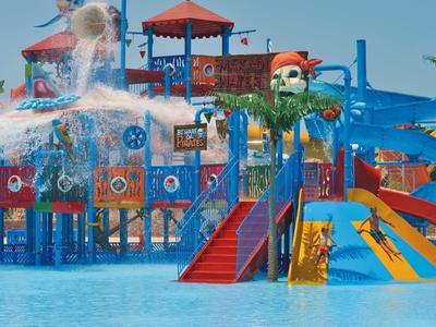 Buntes Wasserspielplatz mit Rutschen, Wassereimer, Piratendekor und Spritzern im blauen Pool.