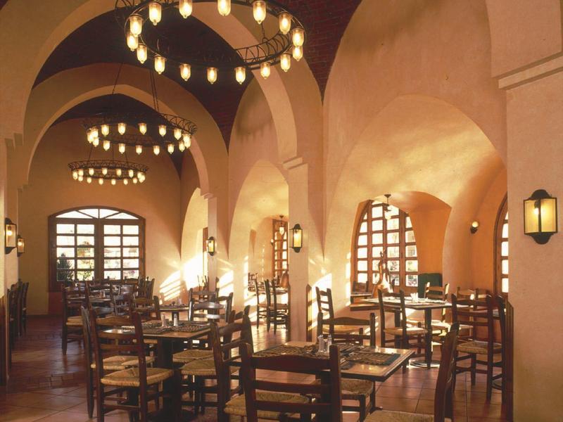 Historisches Restaurant mit hohen Bögen, holzfarbenen Stühlen und warmem Lichtschein.