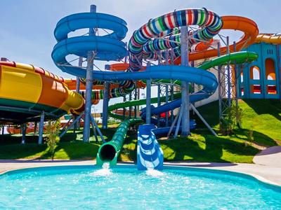Bunte Wasserrutschen führen in ein klares Schwimmbecken an sonnigem Himmel.