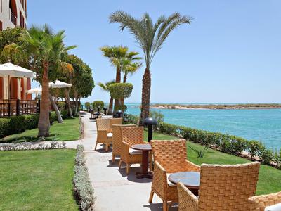 Terraza del hotel con sillas a lo largo de un camino con vistas al mar bajo un cielo despejado.