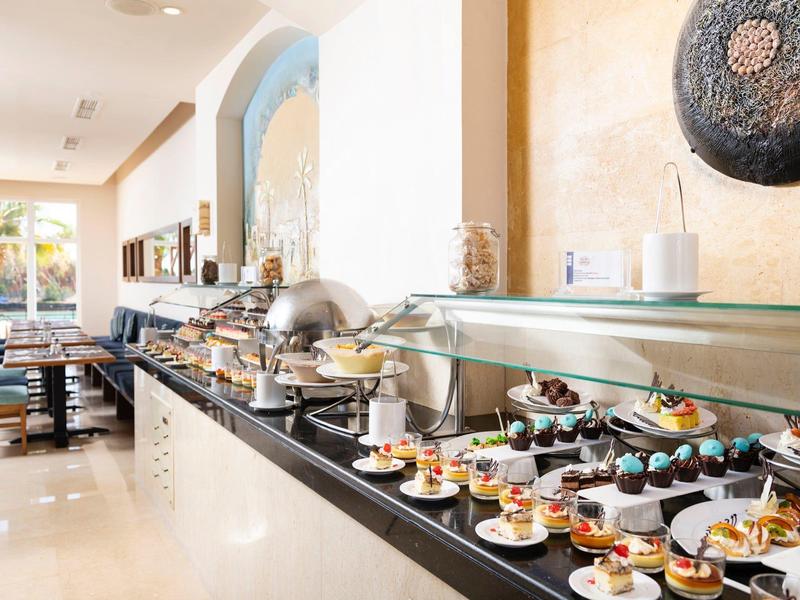 Buffet with various desserts and breakfast items in a bright, modern dining area.