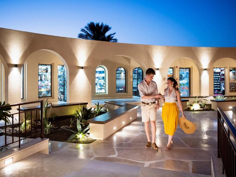 Couple walking on a stone terrace with arches and evening lighting.