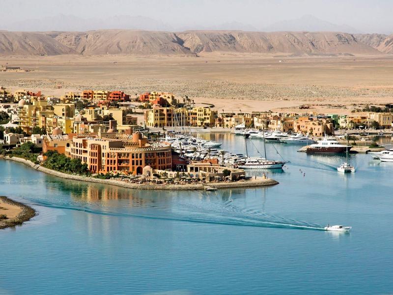 Resort with buildings on a small peninsula surrounded by blue water and desert mountains.