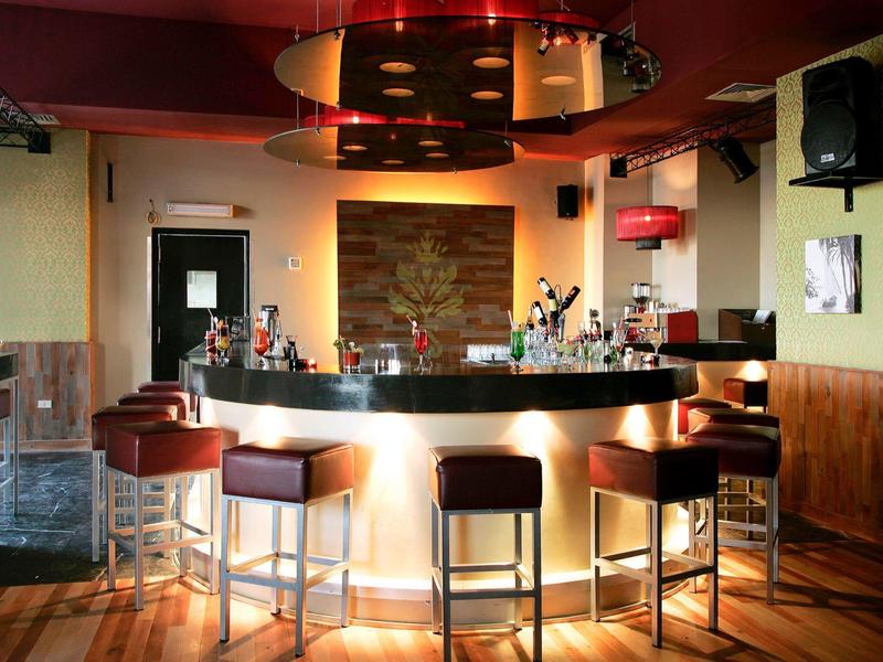 Cozy bar with illuminated counter, bar stools, wooden floor, and warm lighting.