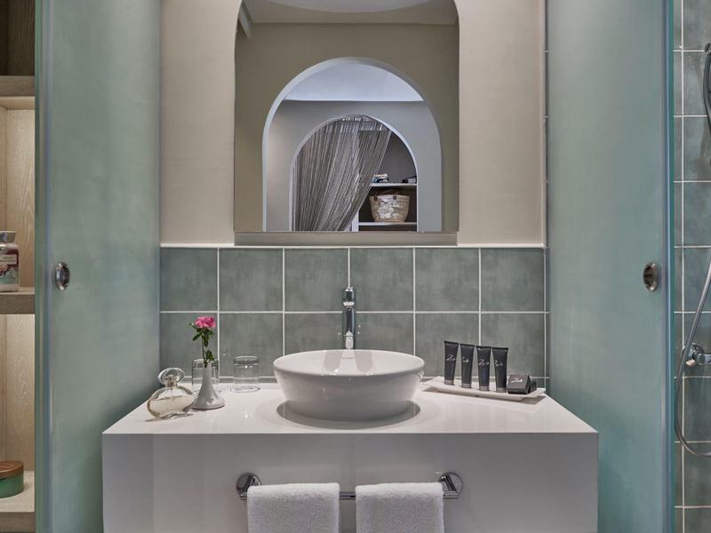 Modern bathroom with round sink, green tiles, and towels on rack under the counter.