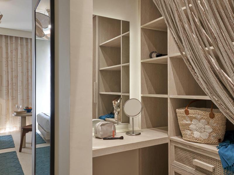 Cozy hotel room with a vanity desk, mirror, wicker basket, and sheer curtain.