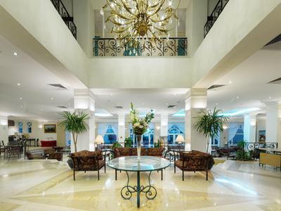 Elegante Hotellobby mit Kronleuchter, Sitzgruppen und Pflanzen auf hellem Marmorboden