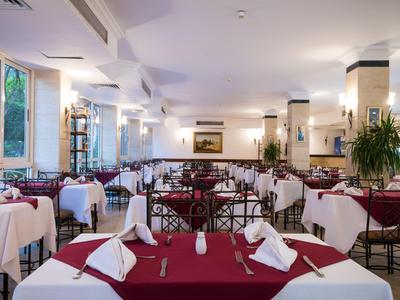 Ein eleganter Speisesaal mit rot-weißen gedeckten Tischen und großen Fenstern.