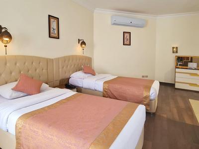 Gemütliches Schlafzimmer mit zwei Einzelbetten, warmen Farben, Kommode und Wandlampen.