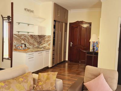 Gemütliches Wohnzimmer mit Sofa, Küchenzeile, Holzfußboden und zwei Türen aus dunklem Holz.