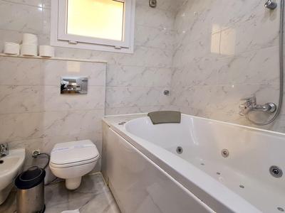 Kompaktes Badezimmer mit weißer Badewanne, WC, Waschbecken und wandhängendem Spiegel.