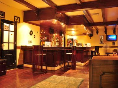 Gemütliche Hotelbar mit Holzdecke, Barhockern und warmem Licht.