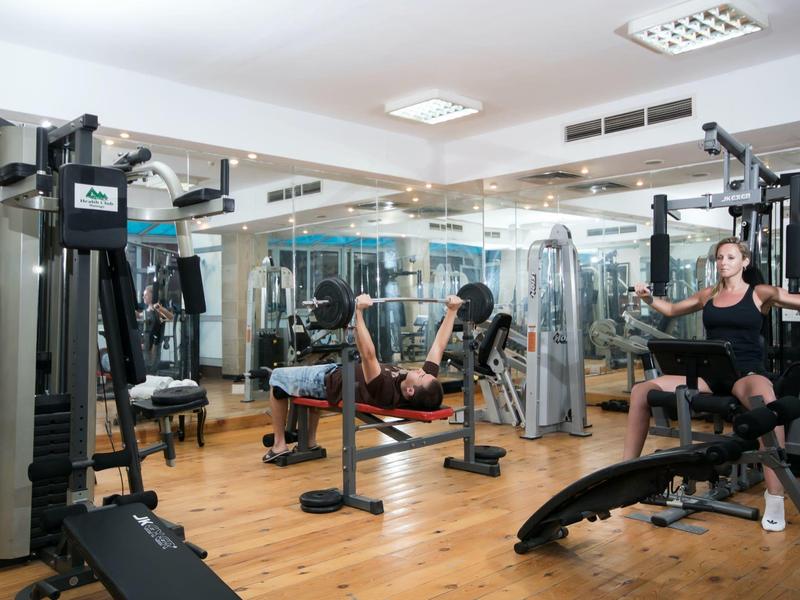 Innenansicht eines Fitnessstudios mit Trainingsgeräten und Personen beim Workout