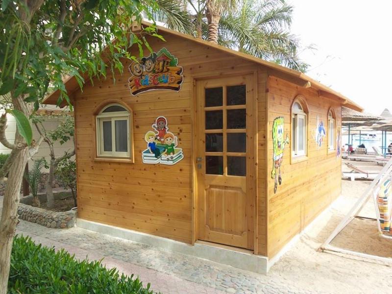 Kleines hölzernes Strandhaus mit bunten Aufklebern und Palmen im Hintergrund.