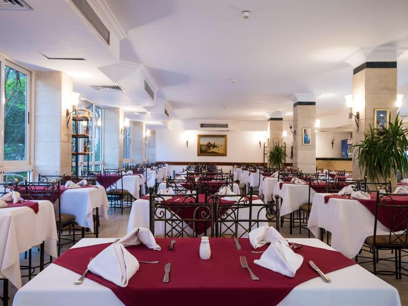 Ein eleganter Speisesaal mit rot-weißen gedeckten Tischen und großen Fenstern.