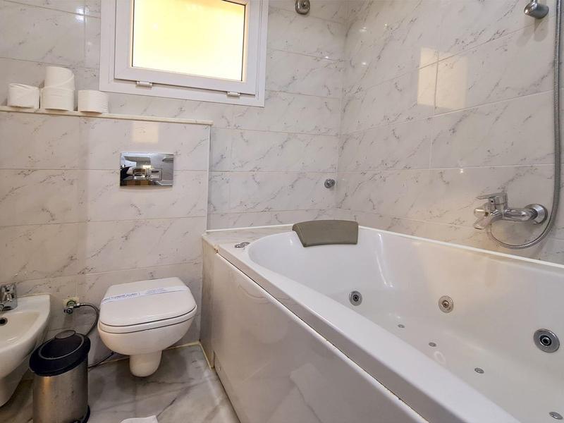 Kompaktes Badezimmer mit weißer Badewanne, WC, Waschbecken und wandhängendem Spiegel.